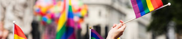 Foto de uma mão segurando uma bandeira do orgulho LGBTI+